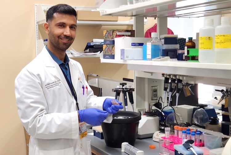 Man standing at lab table in a lab coat