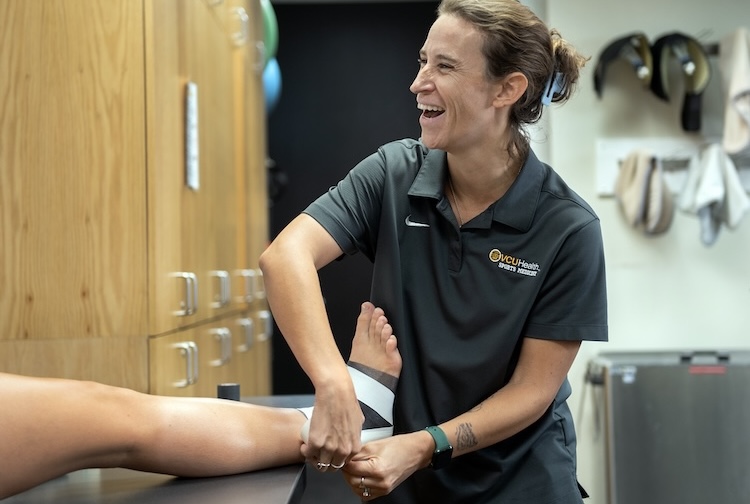 Emily Huss tapes a student’s leg in a clinic