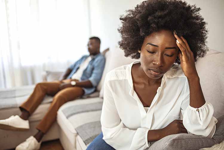 Woman looking distraught as husband sits in background