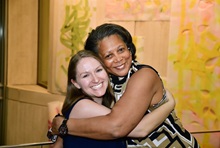 Two women smile as they hug.