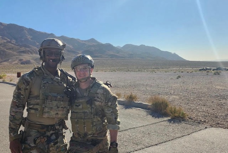 two service members standing on an airforce base with mountains behind them