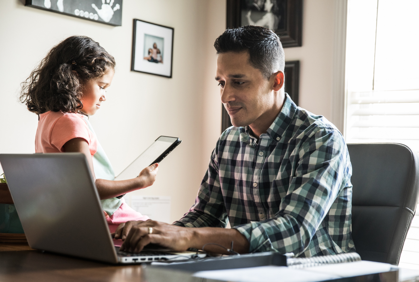 Man working on laptop with child in background