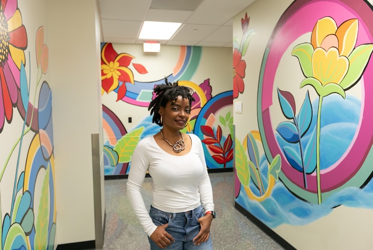 Woman standing in hallway with mural on the walls