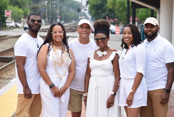 Family photo of the Easters. Everyone is dressed in white and are posing. 