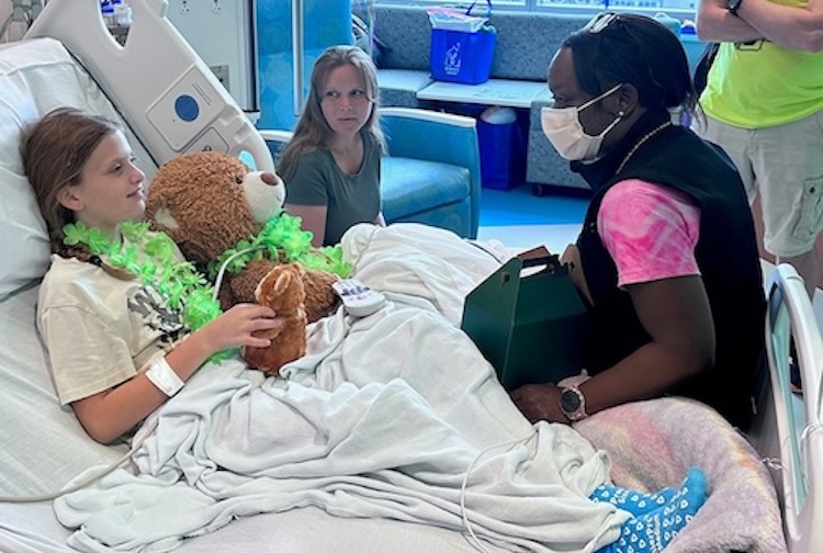 Jeniece Roane sits on a pediatric patient’s bed and speaks with her and her parents.