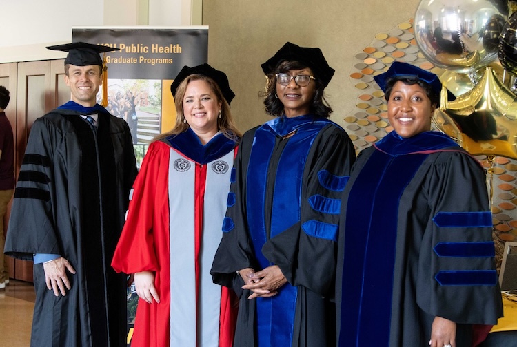 four professors standing together at a graduation ceremony