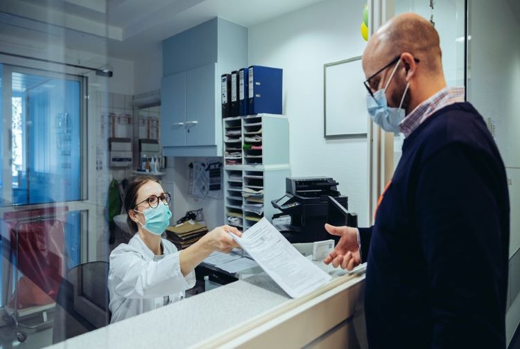 Visitor at reception desk wearing face mask