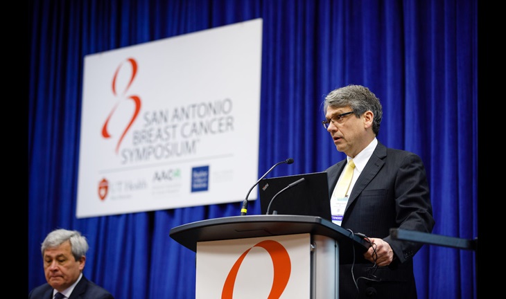 A man in business attire speaks at a lectern.