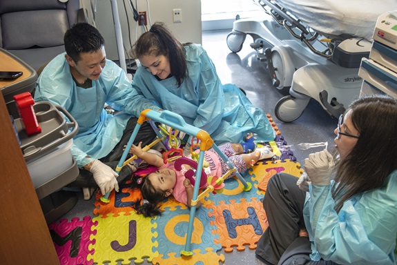 Remy Miller with parents Nicole Arani and Brett Miller and a hospital worker blowing bubbles.