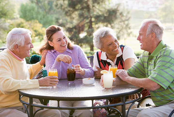 Four people sitting outside at a table and smiling