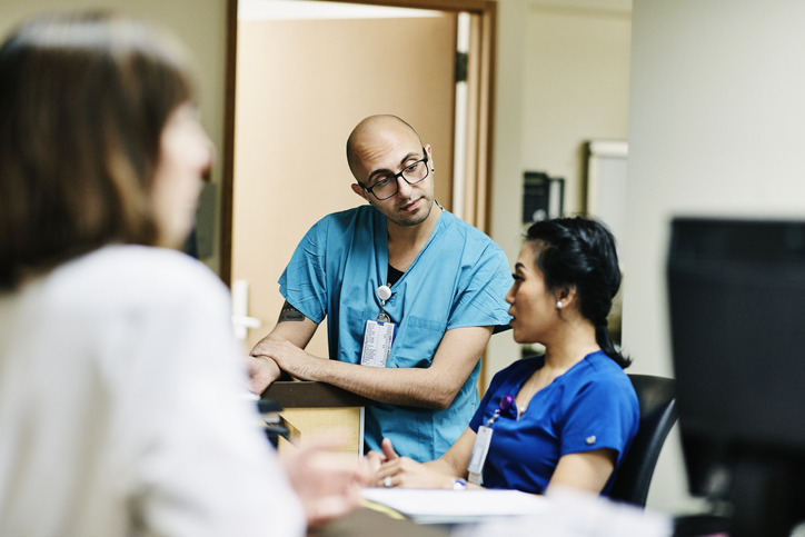 Man and woman sitting beside each other and talking at a desk in a hospital