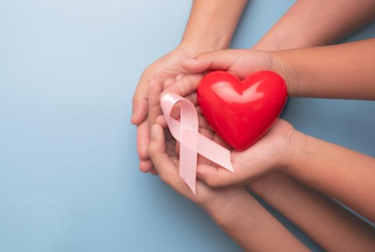 hands holding a heart and a breast cancer ribbon